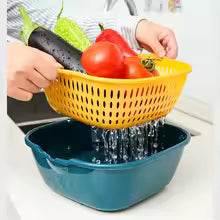 A yellow plastic colander basket being held by hands over a dark blue basin with water draining into it, with vegetables visible inside the basket.